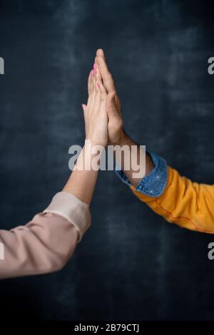 Les mains de deux jeunes professionnels réussis en vêtements de travail se donnant les uns les autres haut cinq tout en se saluant les uns les autres Banque D'Images