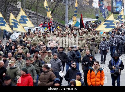 Foule de personnes avec drapeaux pendant le mois de mars.Des Milliers de militaires et de volontaires ukrainiens ont participé à la marche des patriotes marquant la Journée des volontaires honorant les soldats qui ont rejoint l'armée ukrainienne pendant un conflit militaire dans l'est de l'Ukraine. Banque D'Images