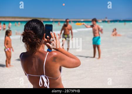 STINTINO, ITALIE - 21 AOÛT 2017 - une femme non identifiée prend des photos sur la célèbre plage de la Pelosa sur l'île de Sardaigne. Banque D'Images