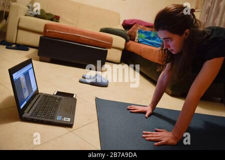 Turin, Italie. 14 mars 2020. Turin, ITALIE - 14 mars 2020: Une fille suit un cours de yoga en ligne de sa maison. Le gouvernement italien a imposé des restrictions sans précédent pour mettre fin à la propagation de l'épidémie de coronavirus COVID-19, entre autres mesures, les mouvements de personnes ne sont autorisés que pour le travail, l'achat de biens essentiels et pour des raisons de santé. (Photo De Nicolò Campo/Sipa Usa) Crédit: Sipa Usa/Alay Live News Banque D'Images