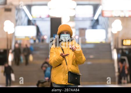 La jeune européenne femme en masque de protection jetable médical à l'aide d'antiseptique dans le métro. Nouveau coronavirus (COVID-19). Concept de voiture de santé Banque D'Images