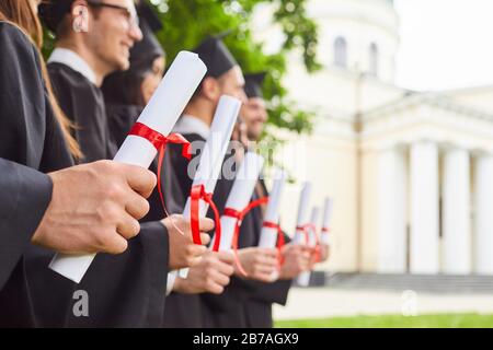 Rouleaux de diplômes entre les mains d'un groupe de diplômés. Banque D'Images