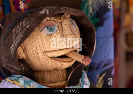 Tête tissée fumant un dooby tissé portant une robe traditionnelle à l'extérieur d'une boutique d'Essaouira, Maroc Banque D'Images
