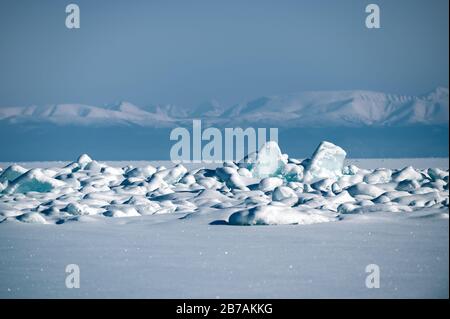 Floes de glace bleu transparent entassées dans des hummocks de glace contre un ciel bleu par temps ensoleillé. Paysage hivernal inhabituel du lac gelé Baikal. Froid naturel b Banque D'Images