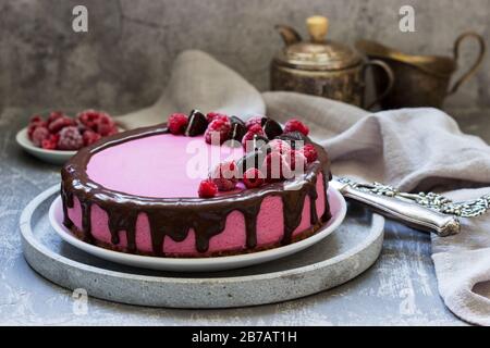 Gâteau à la mousse de curricassis décoré de petits gâteaux et de framboises. Banque D'Images