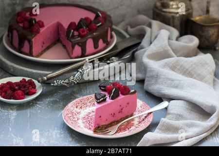 Gâteau à la mousse de curricassis décoré de petits gâteaux et de framboises. Banque D'Images