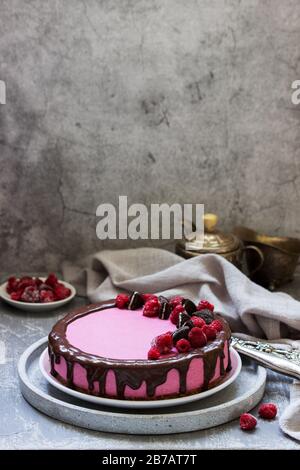 Gâteau à la mousse de curricassis décoré de petits gâteaux et de framboises. Banque D'Images