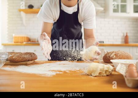 L'homme barbu de Baker fait de la pâte à pain fraîche à une table dans la cuisine de boulangerie. Banque D'Images