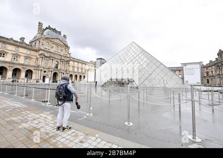 Paris, France. 14 mars 2020. Un homme se tient devant le musée du Louvre fermé à Paris, en France, le 14 mars 2020. Après avoir interdit les rassemblements de plus de 100 personnes et fermé toutes les pépinières et les écoles, la France a annoncé samedi un arrêt national de tous les lieux publics non essentiels dans une nouvelle démarche pour stopper la propagation de COVID-19. Samedi, les cas d'infection par le COVID-19 en France ont doublé pour atteindre 4 500 en 72 heures, dont 91 sont morts. Crédit: Jack Chan/Xinhua/Alay Live News Banque D'Images