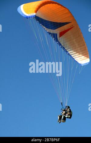 Parapentes en tandem avec parachute jaune orange blanc et bleu à Oludeniz en Turquie Banque D'Images