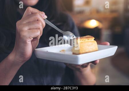 Gros plan image d'une femme tenant et gâteau au fromage avec cuillère à manger dans le café Banque D'Images