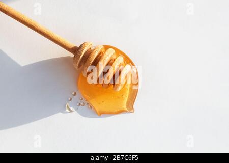 Balancier miel en bois dans miel sur fond blanc Banque D'Images