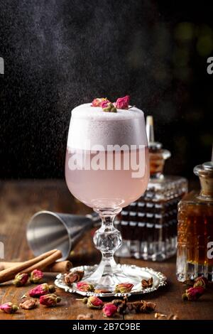 Cocktail rose femelle avec de la mousse dans un verre. décorées de rose séchée. dans l'arrière-plan est visible inventaire barman Banque D'Images