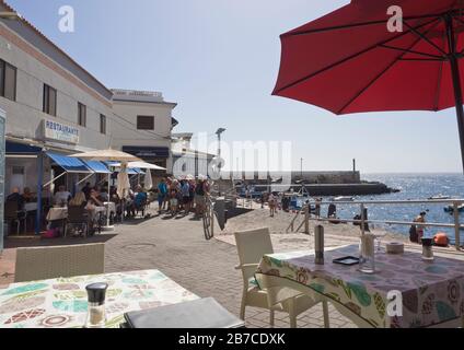 Dans le port de pêche de Los Abridges, Tenerife îles Canaries Espagne les touristes apprécient la mer, le soleil et les fruits de mer protégés par le brise-lames Banque D'Images