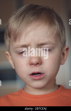 Garçon de cinq ans avec nez liquide allergique et yeux fermés. Banque D'Images