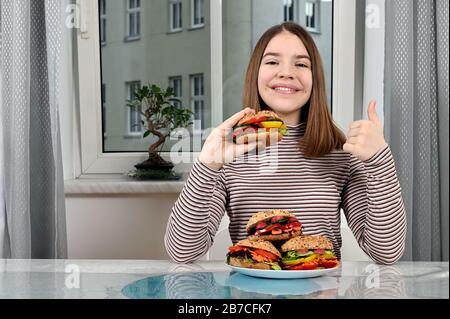 bonne fille avec des sandwichs végétaliens et un pouce vers le haut Banque D'Images