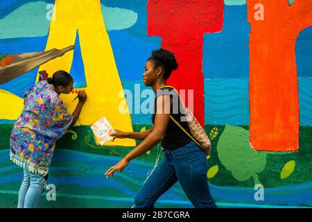 Les étudiantes afro-colombiennes peignent une fresque liée à la société et à l'environnement sur un mur scolaire à Quibdó, Colombie. Banque D'Images