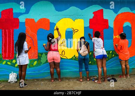 Les étudiantes afro-colombiennes peignent une fresque liée à la société et à l'environnement sur un mur scolaire à Quibdó, Colombie. Banque D'Images