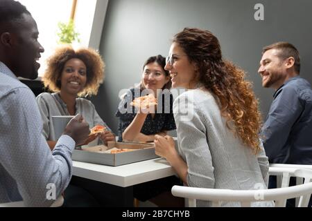 Joyeux collègues qui s'amusent et apprécient la pizza au bureau Banque D'Images