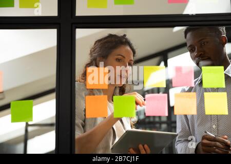 Mentor expliquant le plan du projet sur les autocollants au stagiaire afro-américain Banque D'Images