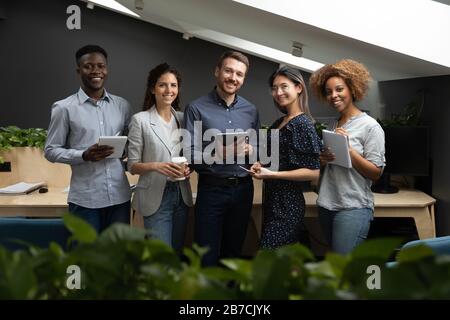 Portrait de l'équipe réussie de divers employés qui tient des appareils électroniques Banque D'Images