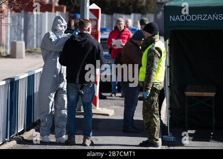 15 mars 2020, Saxe, Görlitz: Un homme dans un costume de protection vérifie la température corporelle d'un passant avec un thermomètre sur le pont de l'amitié à la frontière polonaise au large de Zgorzelec à l'est de la rivière Neisse. La Pologne a fermé ses frontières avec l'Allemagne et d'autres pays voisins de l'UE aux étrangers de la nuit au dimanche en raison de la crise du coronavirus. Photo: Sebastian Kahnert/dpa-Zentralbild/dpa Banque D'Images