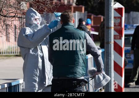 15 mars 2020, Saxe, Görlitz: Un homme dans un costume de protection vérifie la température corporelle d'un passant avec un thermomètre sur le pont de l'amitié à la frontière polonaise au large de Zgorzelec à l'est de la rivière Neisse. La Pologne a fermé ses frontières avec l'Allemagne et d'autres pays voisins de l'UE aux étrangers de la nuit au dimanche en raison de la crise du coronavirus. Photo: Sebastian Kahnert/dpa-Zentralbild/dpa Banque D'Images