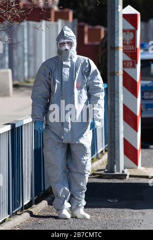 15 mars 2020, Saxe, Görlitz: Un homme en costume de protection se tient devant un poste frontalier sur le pont de l'amitié à la frontière polonaise à l'extérieur de Zgorzelec à l'est de la rivière Neisse. La Pologne a fermé ses frontières avec l'Allemagne et d'autres pays voisins de l'UE aux étrangers pendant la nuit du dimanche au dimanche en raison de la crise du coronavirus. Photo: Sebastian Kahnert/dpa-Zentralbild/dpa Banque D'Images