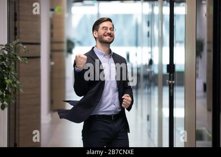 Joyeux jeune employé dansant au bureau pour célébrer le succès Banque D'Images