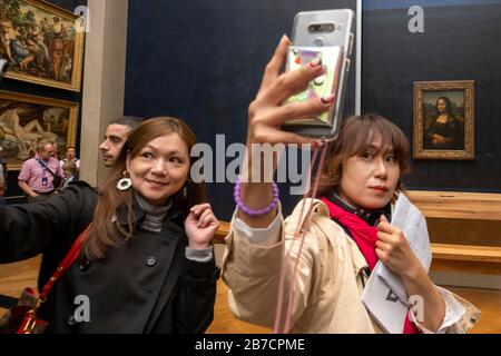 Les touristes asiatiques utilisant leurs smartphones pour prendre des selfies avec la peinture Mona Lisa de l'artiste Leonardo da Vinci, Musée du Louvre, Paris, France, Europe Banque D'Images