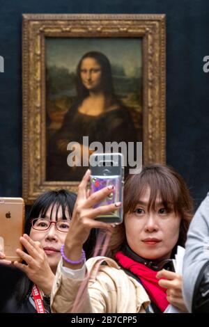Les touristes asiatiques utilisant leurs smartphones pour prendre des selfies avec la peinture Mona Lisa de l'artiste Leonardo da Vinci, Musée du Louvre, Paris, France, Europe Banque D'Images
