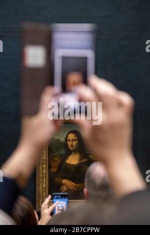 Les touristes utilisant leurs smartphones pour prendre des photos de la peinture de la Mona Lisa par l'artiste Leonardo da Vinci, Musée du Louvre, Paris, France, Europe Banque D'Images