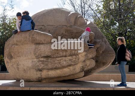 Les enfants qui jouent sur une tête géante en pierre avec une sculpture à main en coupe 'Étoute' de l'artiste français Henri de Miller à Paris, France, Europe Banque D'Images