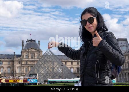 Tourisme posant pour la photographie tout en prétendant tenir la pointe de la pyramide de verre devant le Musée du Louvre à Paris, France, Europe Banque D'Images