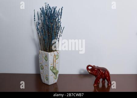 Vase avec lavande préservée et éléphant indien symbole de prospérité, richesse et stabilité sur une poitrine brune en bois. CopySpace. Banque D'Images