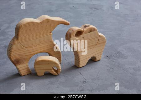 Jouets en bois. Une famille de 3 éléphants sculptés dans un puzzle sur un fond de béton gris. Symbole d'une famille heureuse et forte. Banque D'Images
