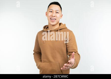 Homme asiatique dans le hoodie brun avec des bras ouverts sur un fond blanc Banque D'Images
