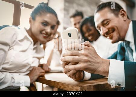 Diverses équipes d'employés regardent des photos dans le téléphone mobile Banque D'Images