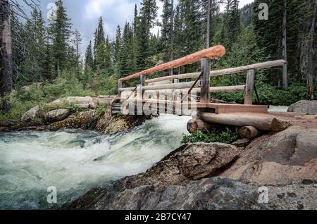 Pont de pied en bois sur la glace fondre la rivière Raging dans les montagnes Grand tetons près du lac Jenny et point d'inspiration Wyoming USA Banque D'Images