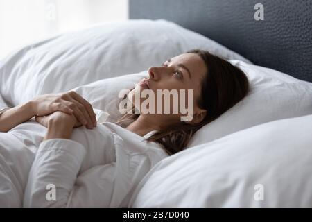 Jeune femme mécontente posée au lit souffrant d'insomnie. Banque D'Images