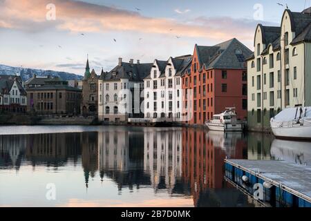 Une photo au coucher du soleil de beaux bâtiments reflétant l'eau, prise à Aalesund, Norvège. Banque D'Images