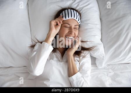 Jeune femme riant, en prenant le masque de sommeil après le repos de nuit. Banque D'Images