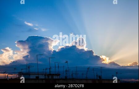 Rayons de soleil parmi les nuages au-dessus des antennes sur les toits de la ville Banque D'Images