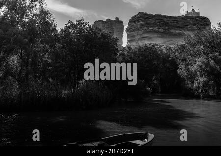 Bateau sur la rivière et le château au sommet de Les rochers à Alcalá del Júcar en noir et blanc Banque D'Images
