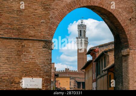 Torre del Mangia, le clocher ou le campanile, à côté du Palais de la ville (Palazzo çm'Agata) vu à travers la Porta Sant'Agata, Sienne, Toscane, Italie Banque D'Images