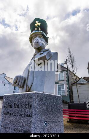 Ardara, Comté de Donegal, Irlande. 15 mars 2020. Le buste du célèbre joueur irlandais de violon, John Doherty, est orné d'un masque et d'un chapeau qui se moquent du coronavirus actuel, Covid-19, pandémie. La parade de la Saint-Patrick de la ville a été annulée avec la plupart de ces défilés en Irlande. Banque D'Images