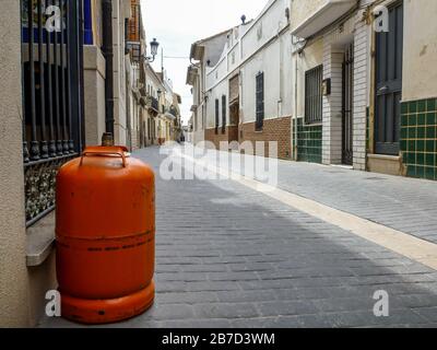 Bouteille de gaz orange dans une rue calme d'un village Banque D'Images