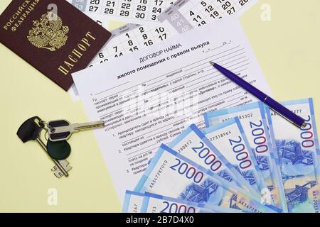 La forme du document avec le texte russe de l'accord de location avec le droit de rachat. Passeport, clés et argent sur la table. Location ho Banque D'Images