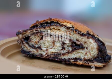 Gâteau à la pâte de levure, forme de rouleau, rempli de chocolat aromatisé, cuisson maison, fait à la main, sur une plaque d'or, fond flou. Banque D'Images