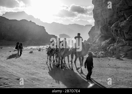 WADI RUM, JORDANIE - 31 JANVIER 2020 : ciel impressionnant avec des rayons de soleil sur les personnes qui font des chameaux. Image en noir et blanc, nuages bouffis d'hiver ciel de l'après-midi. Désert, Royaume hachémite de Jordanie Banque D'Images